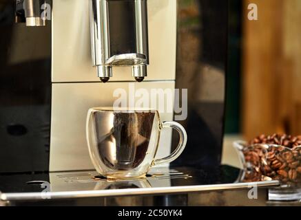 Une machine à café prépare un espresso dans une tasse transparente. Concept de café fraîchement préparé. Banque D'Images