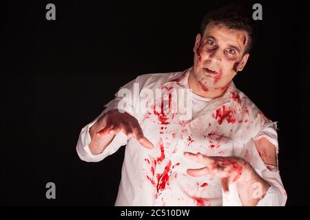 Homme portant un costume de zombie sanglant sur fond noir pour halloween. Maquillage créatif. Banque D'Images