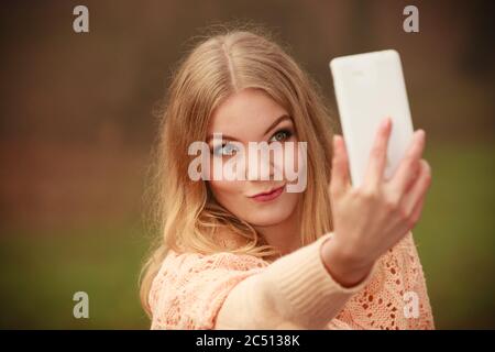 Photographie les gens concept. Jeune fille blonde en tenant un. selfies Belle femme prend photo avec téléphone mobile. Banque D'Images