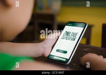 Enseignement en ligne la salle de classe numérique maternelle à l'école concept. Apprendre par téléphone, site mobile historique. Enfant tenant le smartphone avec activé Banque D'Images