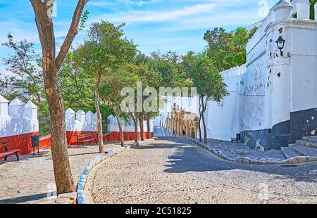 La descente courbe abrupte de la rue Cuesta de Belen avec les murs médiévaux préservés du Palais Ducal Medina Sidonia, Sanlucar, Espagne Banque D'Images