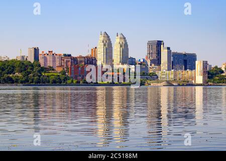 Grande ville sur la rivière large des rives. De belles tours modernes, des bâtiments, des gratte-ciel se reflètent dans l'eau le matin de l'été. Ville ukrainienne Banque D'Images