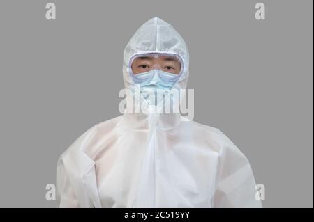 Homme asiatique portant un costume de protection, des masques médicaux et des lunettes sur fond gris. Banque D'Images