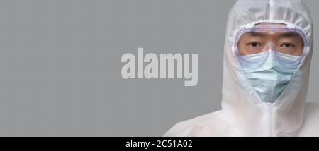 Homme asiatique portant un costume de protection, des masques médicaux et des lunettes sur fond gris. Banque D'Images