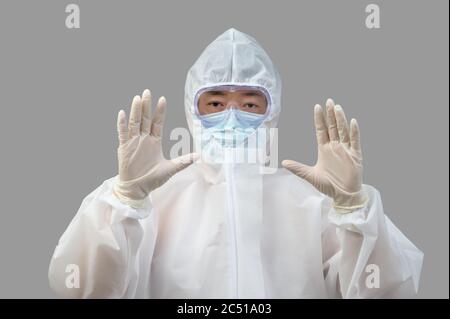 Homme asiatique portant un costume de protection, des masques médicaux et des lunettes sur fond gris. Banque D'Images