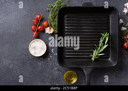 Plat Lay Top vue de dessus poêle en fonte noire pour barbecue. Poêle avec ingrédients de cuisson et épices sur fond de béton avec espace de copie Banque D'Images