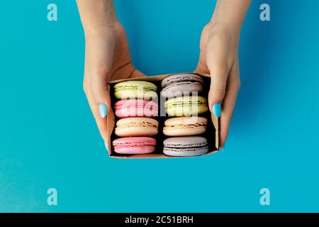 Boîte de mains de femme avec biscuits macarons colorés Banque D'Images