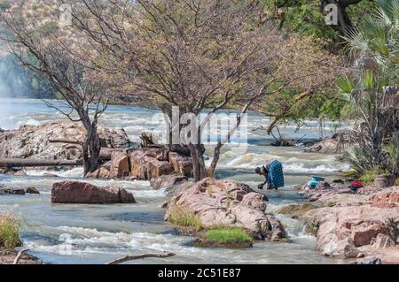 EPUPA, NAMIBIE - 24 MAI 2011 : une femme lavant des vêtements dans la rivière Kunene au sommet des cascades d'Epupa Banque D'Images