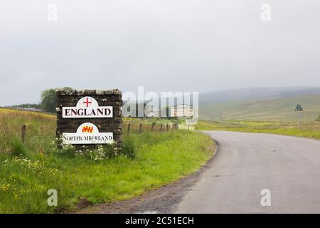 Pilier en pierre et panneaux marquant la frontière entre l'Angleterre et l'Écosse, près d'une route non classée à Deadwater, Kielder, Northumberland, par une journée terne et brumeuse. Banque D'Images