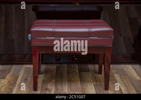 Anciennes clés de piano en bois sur instrument de musique en bois vue de face . banc de piano moderne rouge . Grand piano en bois marron et banc rouge dans la chambre. Banque D'Images