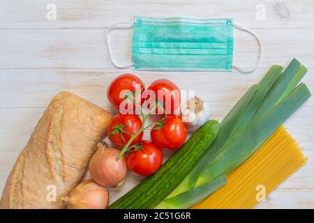 Masque médical de protection et légumes, pain, pâtes alimentaires pour don sur fond de bois. Aide de personnes généreuses. Concept de don. Pose à plat, Banque D'Images