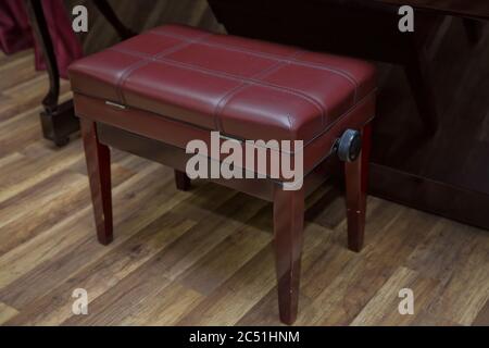 Anciennes clés de piano en bois sur instrument de musique en bois vue de face . banc de piano moderne rouge . Grand piano en bois marron et banc rouge dans la chambre. Banque D'Images