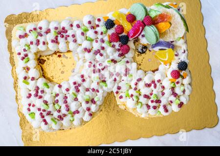 B lettre gâteau d'anniversaire avec bonbons aux fruits et biscuits au citron vert sur la surface dorée. Prêt pour la fête. Banque D'Images