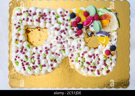 B lettre gâteau d'anniversaire avec bonbons aux fruits et biscuits au citron vert sur la surface dorée. Prêt pour la fête. Banque D'Images