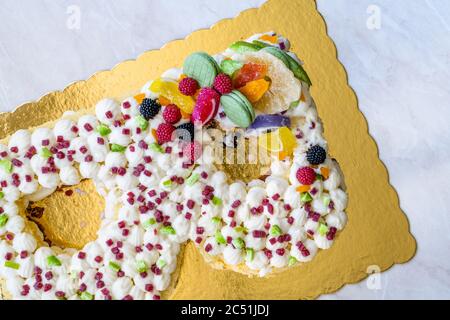 B lettre gâteau d'anniversaire avec bonbons aux fruits et biscuits au citron vert sur la surface dorée. Prêt pour la fête. Banque D'Images