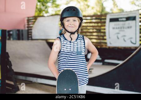 enfant garçon avec skateboard, week-ends, formation, premiers pas à bord. Garçon skateboarder. Jeune enfant souriant tenant le skate Banque D'Images