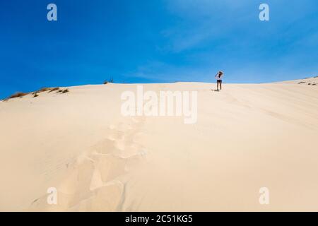 Belle fille caucasienne s'amuser sur les dunes de sable blanc à la Gi, région de Phan Tiet au Vietnam. Paysage avec ciel bleu au sud de Mui ne. Banque D'Images