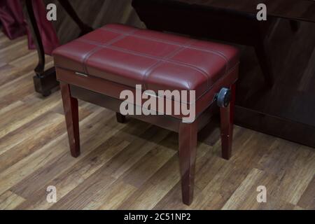 Anciennes clés de piano en bois sur instrument de musique en bois vue de face . banc de piano moderne rouge . Grand piano en bois marron et banc rouge dans la chambre. Banque D'Images