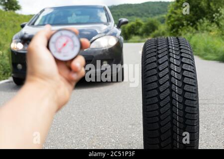 Photo du tout nouveau pneu de la voiture noire sur la route, un jour d'été Banque D'Images