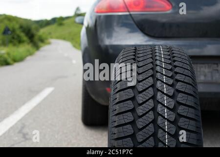 Photo du tout nouveau pneu de la voiture noire sur la route, un jour d'été Banque D'Images