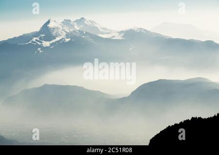 Vue spectaculaire sur les silhouettes des chaînes de montagnes et le brouillard dans les vallées. Vue depuis le sommet du mont Corno di Tres, la corne de Tresner jusqu'à Cima Paganella. Trentin Banque D'Images