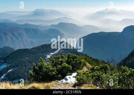 Vue spectaculaire sur les silhouettes des chaînes de montagnes et le brouillard dans les vallées. Vue depuis le sommet du mont Corno di Tres, la corne de Tresner jusqu'à Cima Paganella. Trentin Banque D'Images