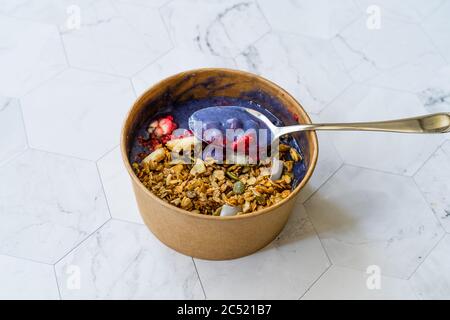 Bol Matcha bleu avec granola, bleuets et banane / Smoothie en papier brun Kraft en boîte. Aliments biologiques sains Superfood. Banque D'Images