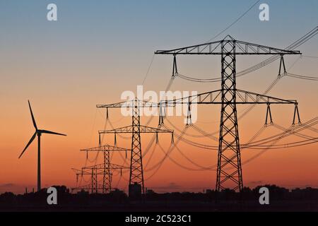 Silhouettes d'une éolienne et de postes électriques pendant le coucher du soleil Banque D'Images
