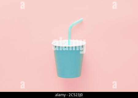 Gobelet en papier bleu avec paille sur fond rose. Vue de dessus de la pose à plat Banque D'Images