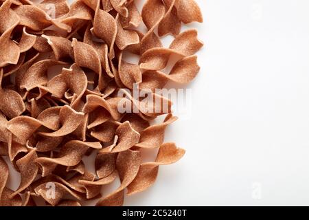 Tas de pâtes de blé entier brutes tagliatella sur fond blanc avec espace de copie. Vue du dessus. Banque D'Images