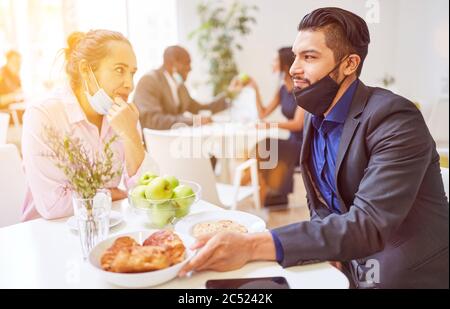 Les hommes d'affaires flirtent avec des protecteurs buccaux sous le menton au café pendant la pause après la pandémie de Covid-19 et de coronavirus Banque D'Images