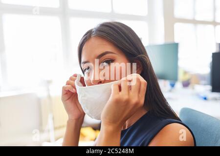 Une jeune femme d'affaires a mis un masque dans le bureau comme une prévention contre Covid-19 Banque D'Images