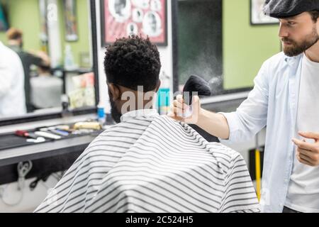 Coiffeur de salon de coiffure de la poudre sur le cou des clients avec une brosse de rasage professionnelle avant de couper les cheveux avec le rasoir. Banque D'Images