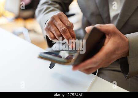 Mains d'un homme d'affaires africain utilisant un smartphone tout en écrivant un message texte Banque D'Images