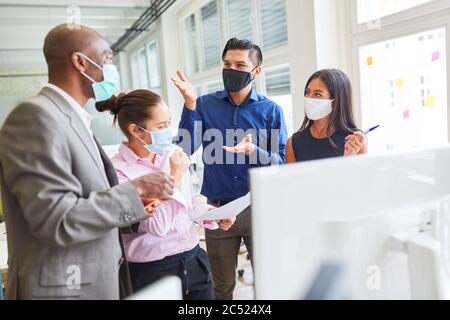 L'équipe de démarrage d'une agence Internet avec masque de visage discute le développement d'un site Web Banque D'Images