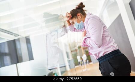 Jeune femme d'affaires stressée au bureau portant un masque facial en raison d'un travail excessif ou d'un arrêt Banque D'Images