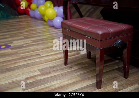 Anciennes clés de piano en bois sur instrument de musique en bois vue de face . banc de piano moderne rouge . Grand piano en bois marron et banc rouge dans la chambre. Banque D'Images