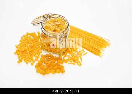 Diverses pâtes non cuites crues et un pot en verre sur fond blanc. Vue du dessus. Banque D'Images