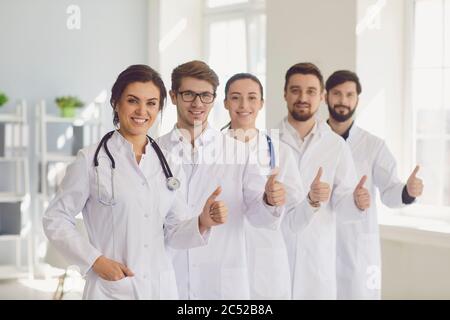 Les jeunes médecins souriants font équipe avec un geste de pouce dans un bureau hospitalier moderne. Banque D'Images