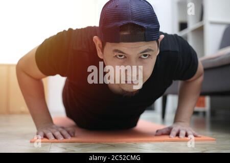 Homme asiatique faisant de l'exercice à la maison pour rester en bonne santé sur le nouveau style de vie normal, à l'intérieur de la maison de l'entraînement concept, les push-up position de planche Banque D'Images