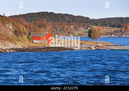 La grange traditionnelle de pêche en bois rouge se trouve sur la côte de la mer norvégienne Banque D'Images