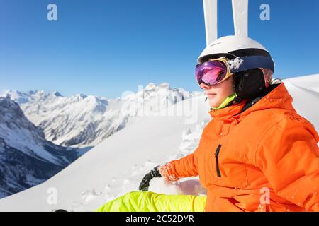 Gros portrait avec masque sur une adolescente en tenue orange près du ski et regarder la montagne Banque D'Images