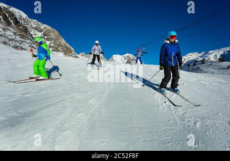 De nombreux enfants skient en descente par beau temps sur la piste alpine se déplaçant en formation libre Banque D'Images