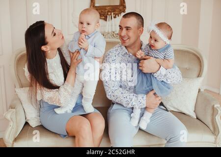 Portrait d'un jeune couple assis sur un canapé avec leurs jumeaux Banque D'Images