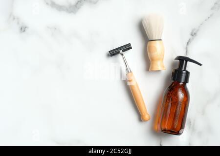 Accessoires de rasage écologiques et flacon en verre ambré avec lotion sur fond de marbre. Flat lay, vue de dessus. Banque D'Images