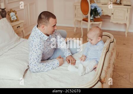 Père assis sur un lit avec son bébé fils Banque D'Images