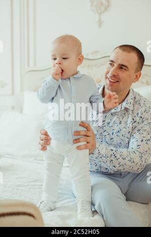Père assis sur un lit avec son bébé fils Banque D'Images