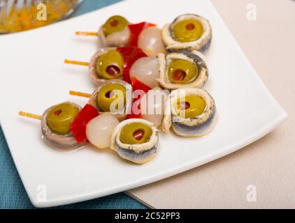 Rouleaux d'anchois marinés appétissant avec olives farcies servies en brochettes avec du poivre et l'oignon rouge Banque D'Images