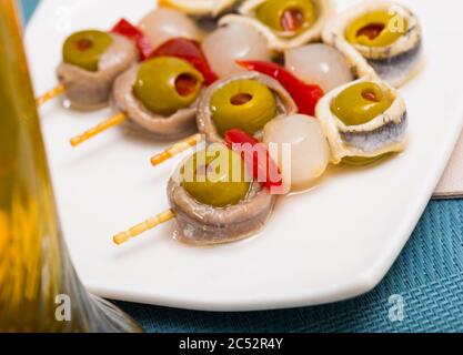 Rouleaux d'anchois marinés appétissant avec olives farcies servies en brochettes avec du poivre et l'oignon rouge Banque D'Images