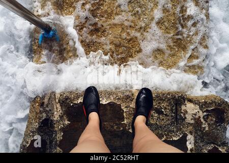 Femme portant des chaussures de natation debout sur des marches dans la mer, Bugibba, Malte Banque D'Images